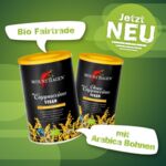 Zwei Dosen veganer Mount Hagen löschlicher Cappuccino und Choco Cappuccino auf grünem Hintergrund mit Bio Fairtrade und Arabica Bohnen Text.