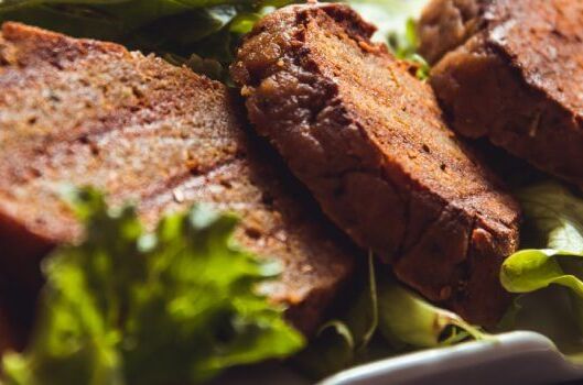 Nahaufnahme von veganen Seitan-Steaks auf frischem grünem Salat angerichtet. Perfekte pflanzliche Fleischalternative!