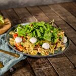Mediterraner veganer Nudelsalat mit getrockneten Tomaten und Rucola.