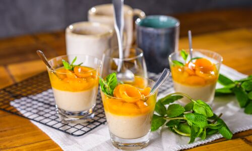 Veganer Pudding im Glas mit fruchtigem Mango-Aprikosen-Topping und frischer Minze, cremiger Vanillepudding ohne Milch und Ei als Dessert angerichtet.