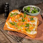 Frisch gebackener veganer Flammkuchen auf Pizzateig mit Vegan Laxx, cremigem Belag, Porree, Paprika und roten Zwiebeln.