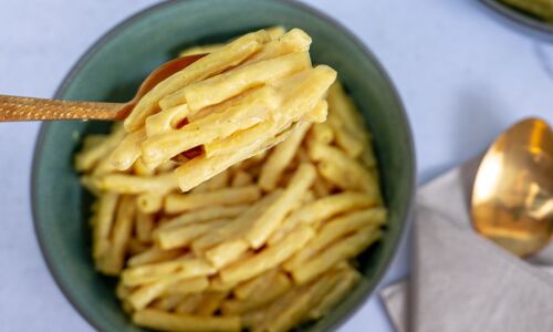 Nahaufnahme einer Schüssel Vegane Mac and Cheese mit cremiger, pflanzlicher Käsesauce, serviert in grüner Schale. Perfekter veganer Genuss!