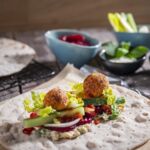 Veganer Falafel Wrap mit frischem Gemüse, Hummus, Salat und knusprigen Falafelbällchen auf dünnem Fladenbrot – ideal für eine pflanzliche Ernährung.