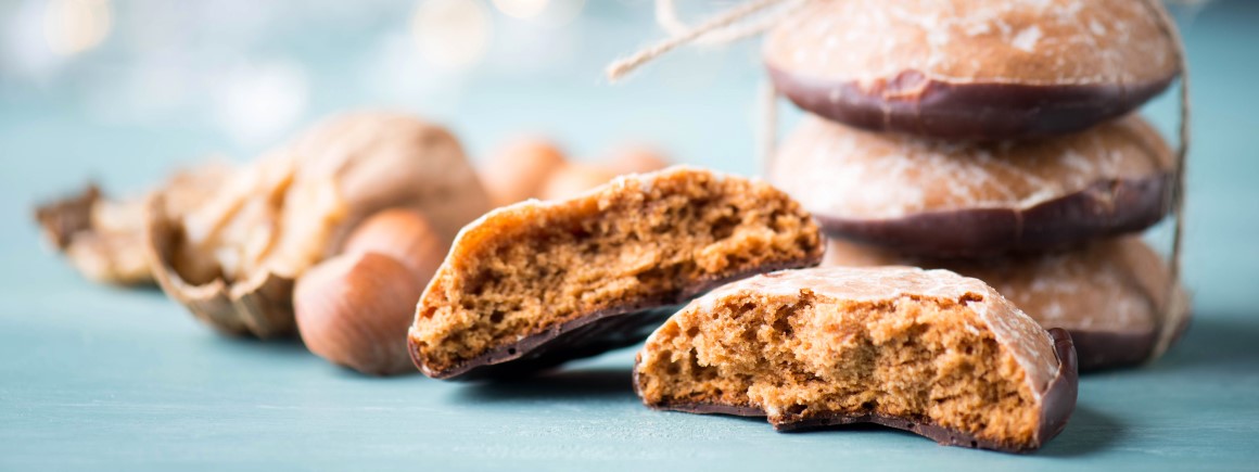 Nahaufnahme von veganen Weihnachtsplätzchen mit Schokoglasur und Nüssen im Hintergrund, perfekt für vegane Weihnachtsbäckerei.