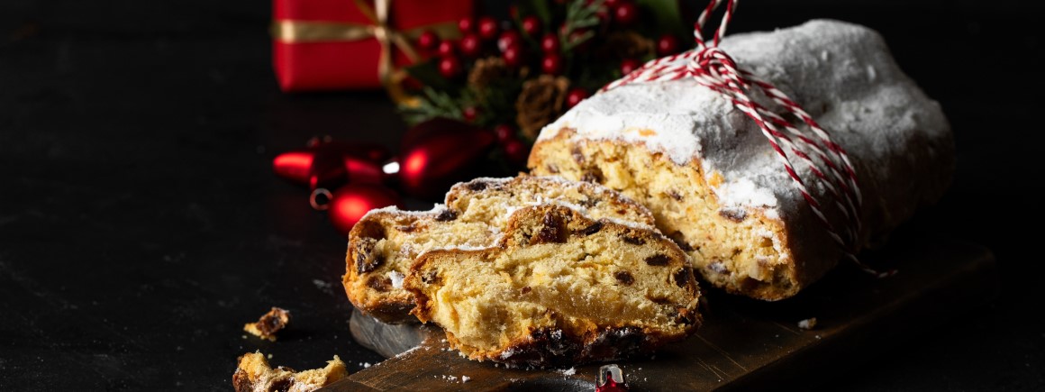 Schmackhafter veganer Weihnachtsstollen mit Puderzucker bedeckt, aufgeschnitten, mit Trockenfrüchten. Ideal für vegane Weihnachtsbäckerei!