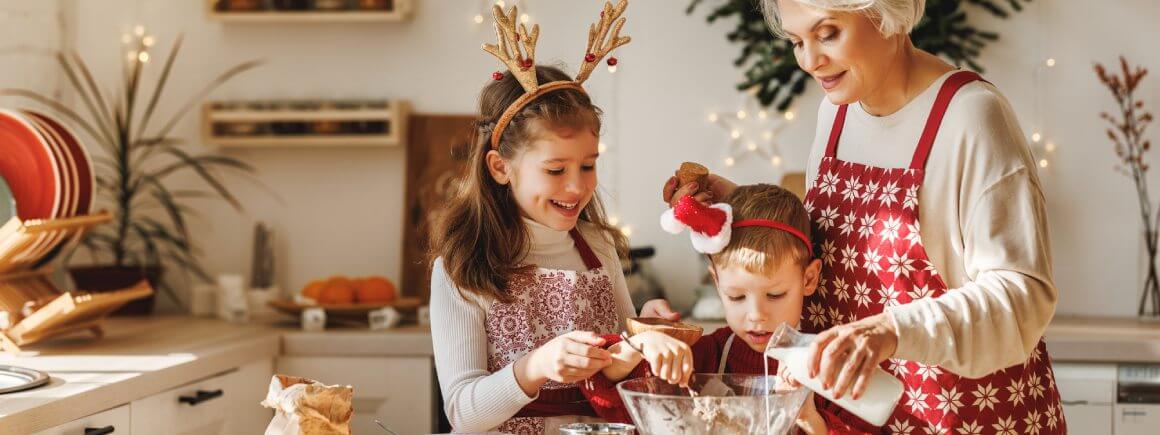 Großmutter und Enkelkinder beim weihnachtlichen Backen mit veganen Zutaten in gemütlicher Küche, festliche Stimmung.